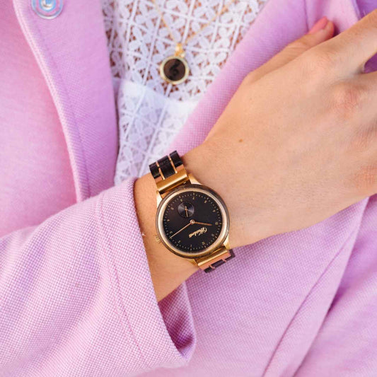 Dámske drevené hodinky Waidzeit Mystik Gold na rukách – kontrast mysticky čierneho duba a zlatej ocele vyžaruje eleganciu a silu prírody