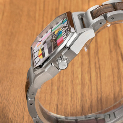 Detail drevených hodiniek Waidzeit Sendeschluss – orechové drevo, motív testovacieho obrazca a elegantný strieborný náramok